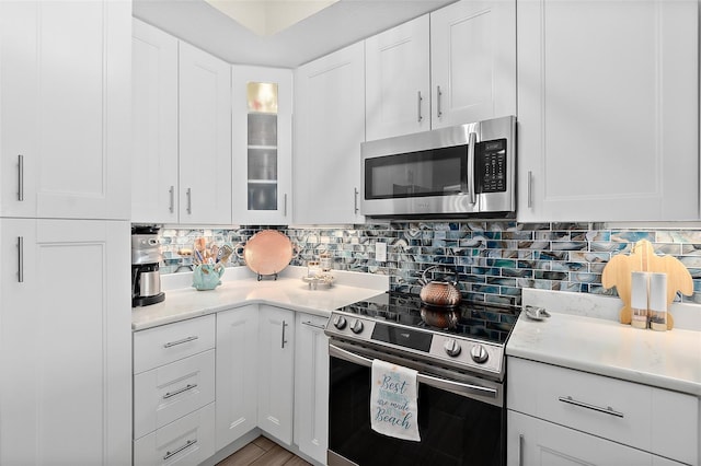 kitchen featuring decorative backsplash, stainless steel appliances, and white cabinets