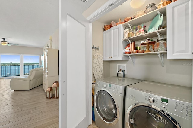 clothes washing area featuring ceiling fan, cabinets, washer and clothes dryer, and light hardwood / wood-style floors