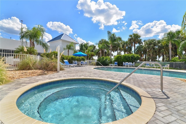 view of pool with a hot tub and a patio