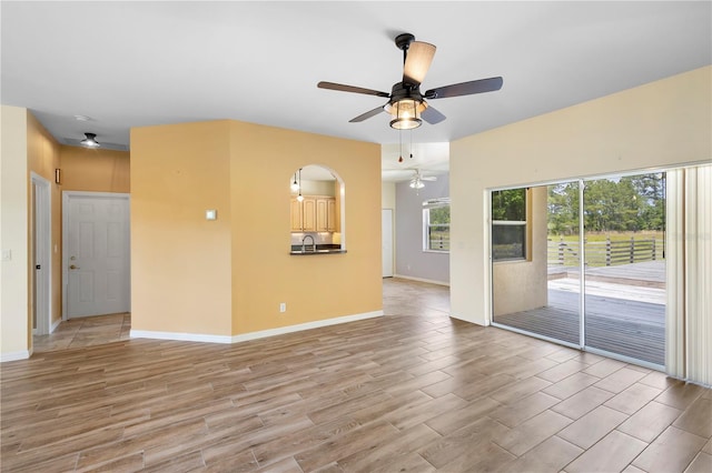 unfurnished room featuring sink, ceiling fan, and light hardwood / wood-style flooring