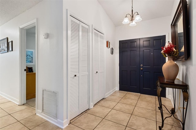 foyer featuring light tile patterned flooring and a chandelier