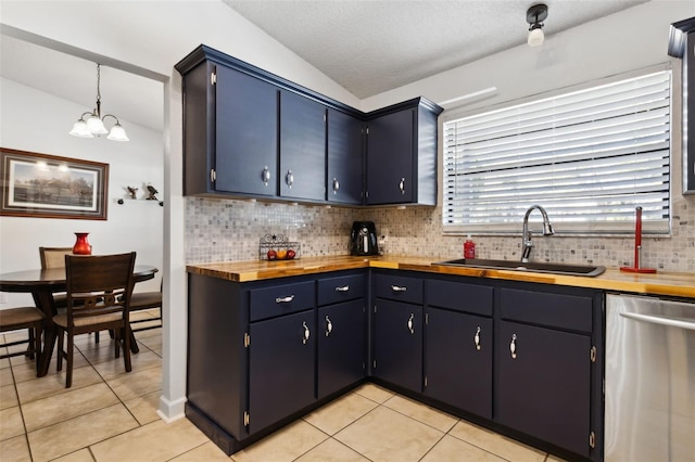 kitchen featuring butcher block countertops, dishwasher, lofted ceiling, sink, and hanging light fixtures