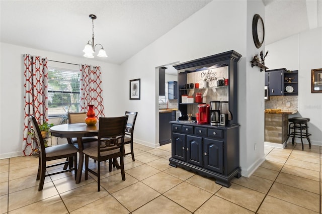 dining area with vaulted ceiling, light tile patterned floors, and a notable chandelier