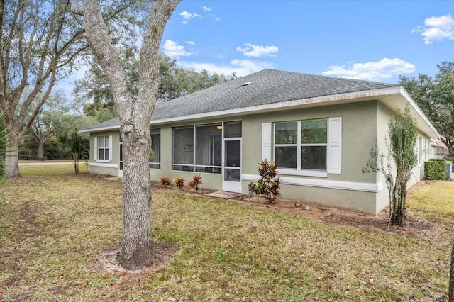 back of property featuring a sunroom and a lawn