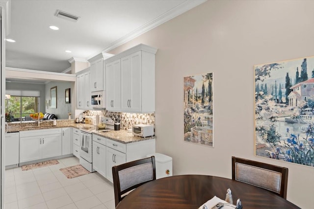 kitchen with white cabinetry, light stone counters, white appliances, and crown molding