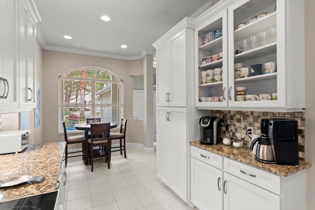 interior space featuring light tile patterned floors, crown molding, white cabinetry, light stone countertops, and decorative backsplash