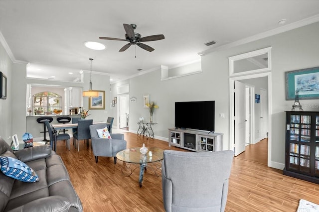 living room featuring crown molding, ceiling fan, and light hardwood / wood-style flooring