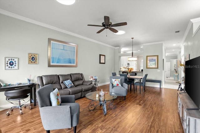 living room featuring ceiling fan, ornamental molding, and light hardwood / wood-style floors