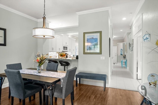 dining area with light hardwood / wood-style flooring and ornamental molding