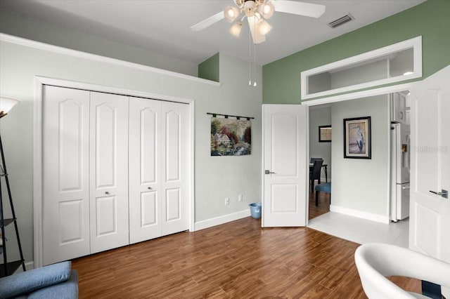 interior space featuring hardwood / wood-style flooring, ceiling fan, fridge with ice dispenser, and a closet