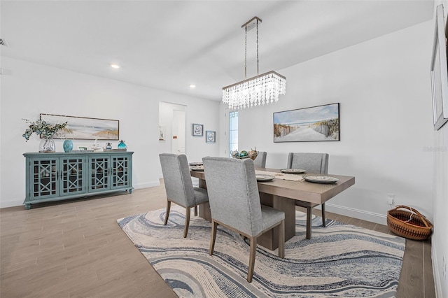 dining space featuring hardwood / wood-style floors and a chandelier