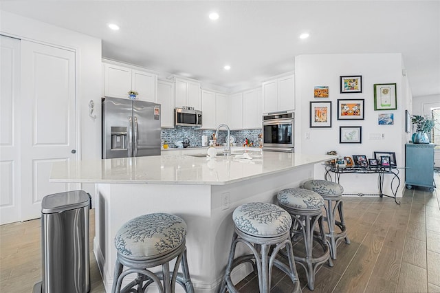 kitchen featuring sink, white cabinetry, a kitchen island with sink, hardwood / wood-style floors, and stainless steel appliances