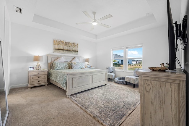 carpeted bedroom with a tray ceiling and ceiling fan