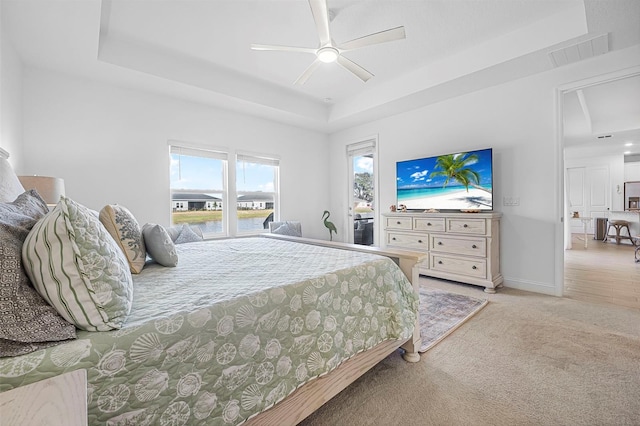 carpeted bedroom with a tray ceiling and ceiling fan