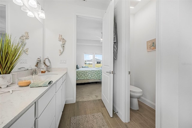 bathroom with hardwood / wood-style flooring, vanity, ceiling fan, and toilet