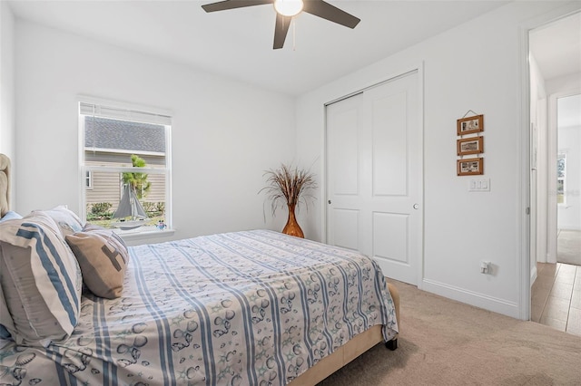 bedroom with ceiling fan, light colored carpet, and a closet