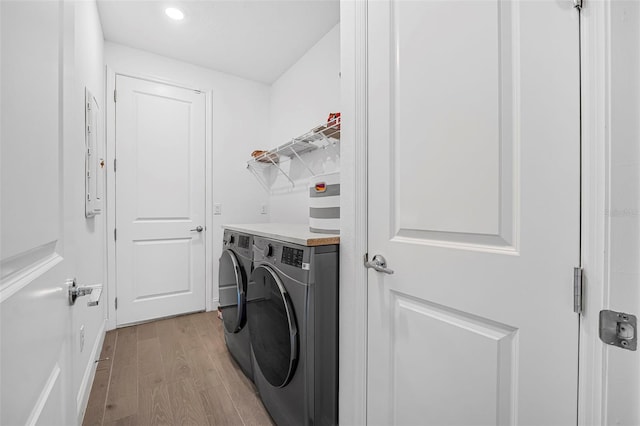 clothes washing area featuring washer and clothes dryer and light hardwood / wood-style floors