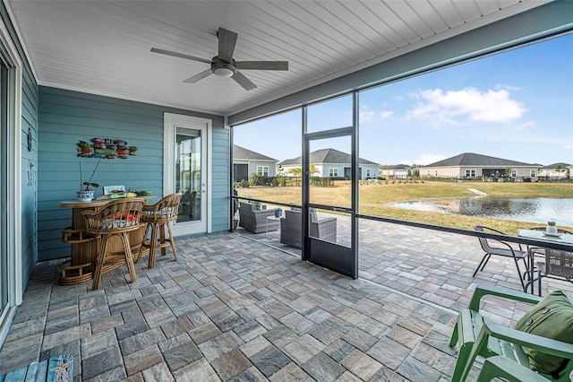 sunroom featuring a water view, indoor bar, and ceiling fan