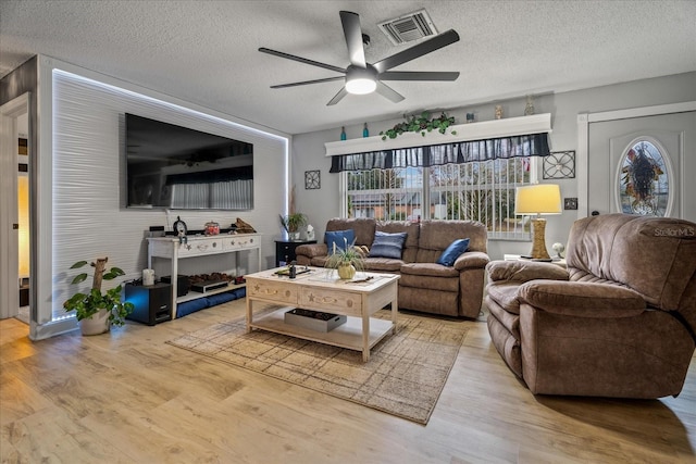 living room featuring ceiling fan, a textured ceiling, and light hardwood / wood-style floors