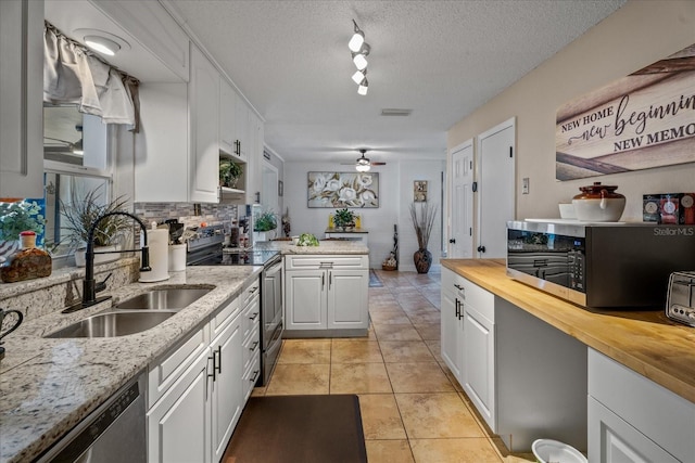 kitchen featuring sink, light tile patterned floors, appliances with stainless steel finishes, white cabinets, and wood counters