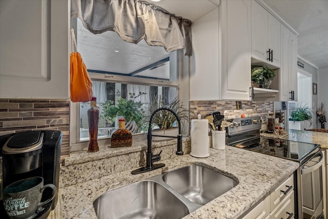 kitchen featuring sink, white cabinetry, stainless steel range with electric stovetop, tasteful backsplash, and light stone countertops