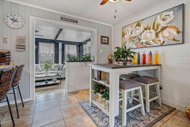 tiled dining room with ornamental molding, ceiling fan, and a textured ceiling