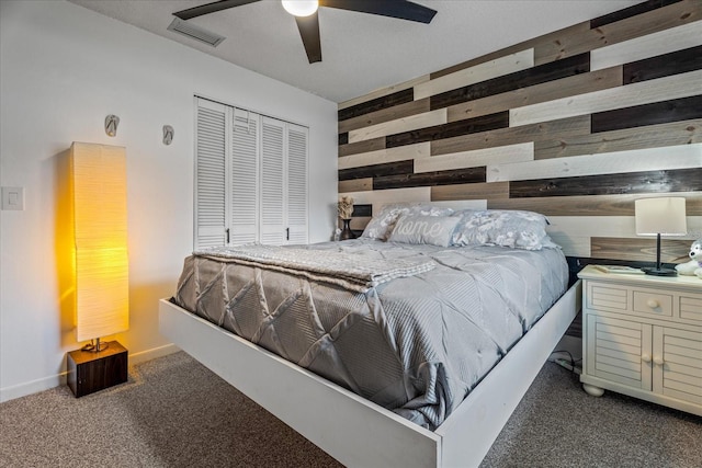 bedroom with wooden walls, a closet, ceiling fan, and dark colored carpet