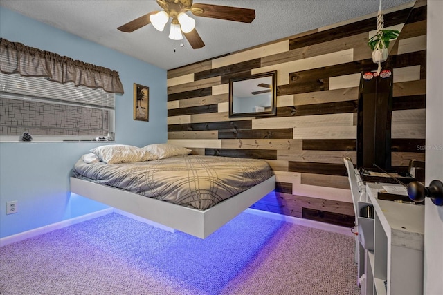 bedroom featuring ceiling fan, wooden walls, a textured ceiling, and carpet flooring