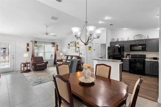 dining room with lofted ceiling, light tile patterned floors, and ceiling fan with notable chandelier