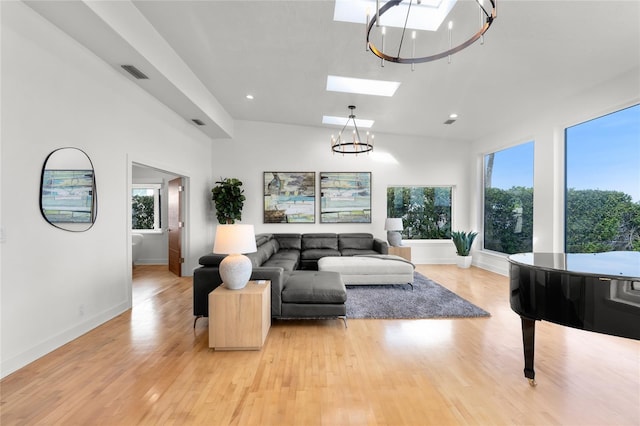 living room featuring a skylight, a chandelier, and light wood-type flooring