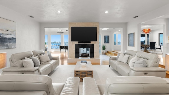 living room with a multi sided fireplace, a chandelier, and light hardwood / wood-style flooring