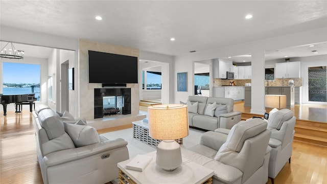 living room with a high end fireplace, a chandelier, and light wood-type flooring