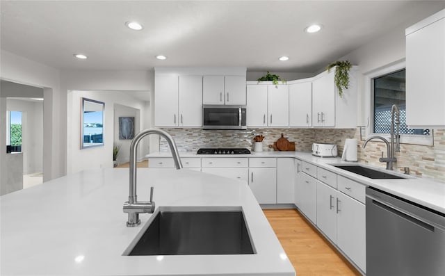 kitchen featuring stainless steel appliances, sink, white cabinets, and light hardwood / wood-style flooring