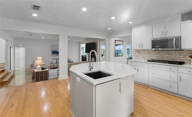 kitchen with sink, a center island with sink, and white cabinets