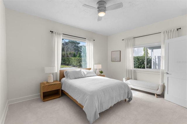 bedroom featuring light carpet, multiple windows, and ceiling fan