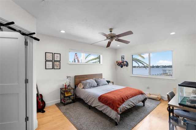 bedroom featuring a water view, ceiling fan, and hardwood / wood-style flooring