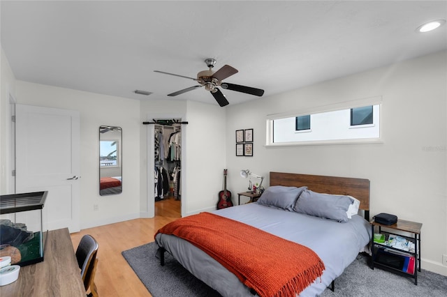 bedroom featuring ceiling fan, a walk in closet, a closet, and light hardwood / wood-style flooring