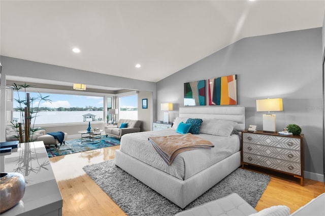 bedroom featuring a water view, lofted ceiling, and hardwood / wood-style floors