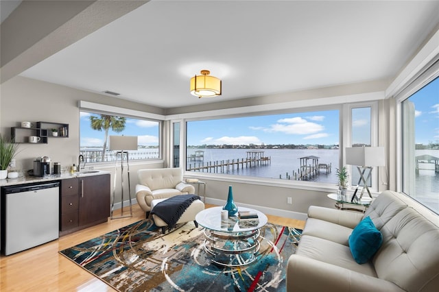 living room with a water view, indoor wet bar, and light wood-type flooring