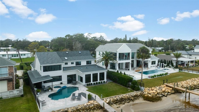 rear view of house featuring a fenced in pool, a lawn, a patio, a water view, and a sunroom