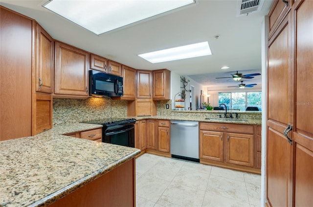 kitchen featuring light stone countertops, sink, kitchen peninsula, and black appliances