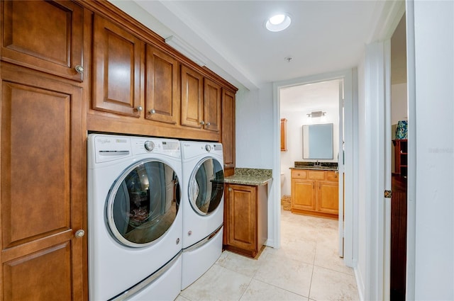 laundry area featuring sink, light tile patterned floors, cabinets, and washing machine and clothes dryer