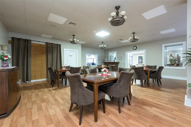 dining room with ceiling fan, a drop ceiling, and light wood-type flooring