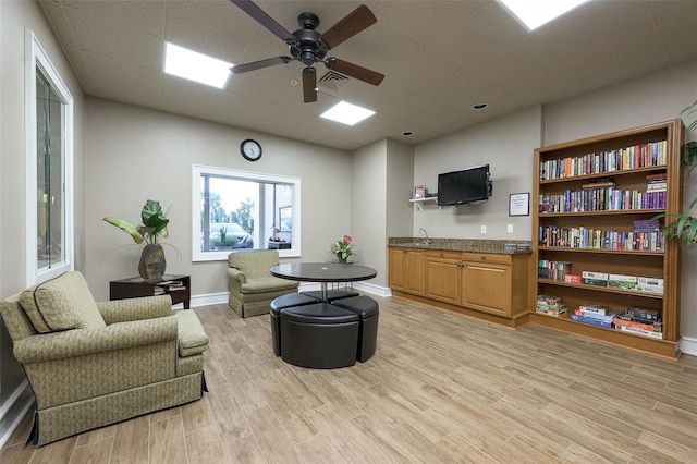 living room featuring a paneled ceiling, light hardwood / wood-style floors, and ceiling fan