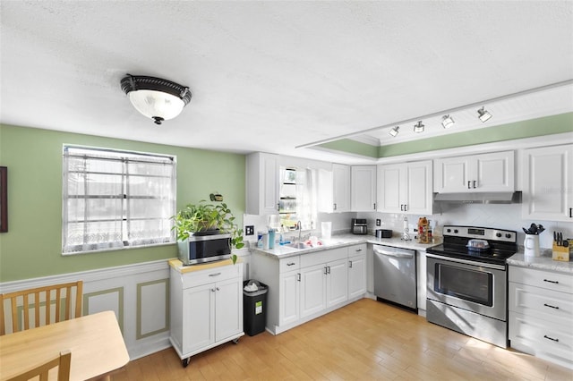 kitchen featuring sink, a textured ceiling, light hardwood / wood-style flooring, appliances with stainless steel finishes, and white cabinets