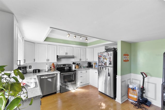 kitchen featuring white cabinetry, appliances with stainless steel finishes, a raised ceiling, and light hardwood / wood-style flooring