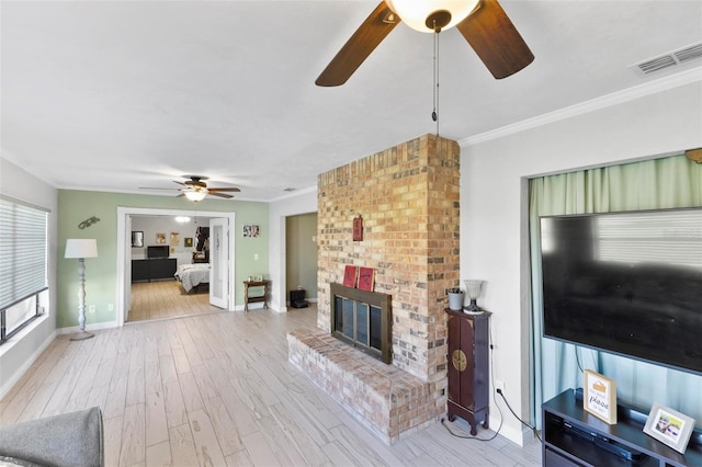 living room featuring crown molding, ceiling fan, a fireplace, and light hardwood / wood-style flooring