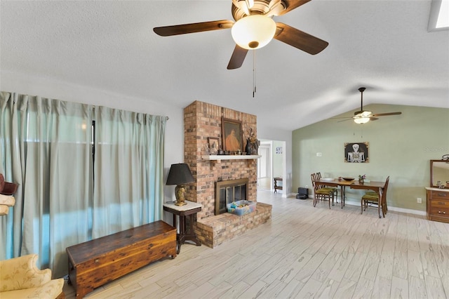 living room featuring vaulted ceiling, a brick fireplace, a textured ceiling, and light hardwood / wood-style floors