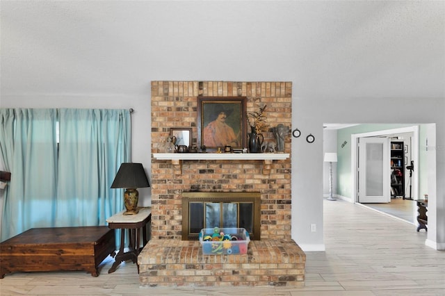 living room featuring a brick fireplace, light hardwood / wood-style flooring, and a textured ceiling