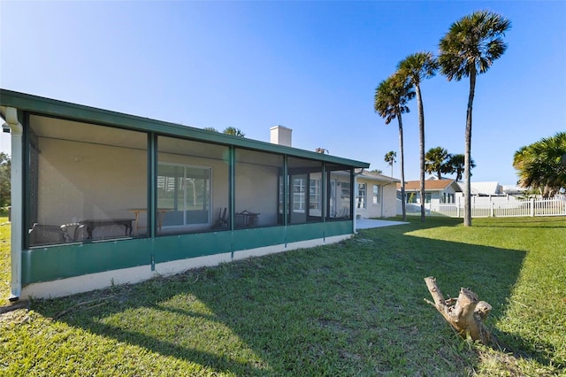 view of home's exterior with a sunroom and a lawn